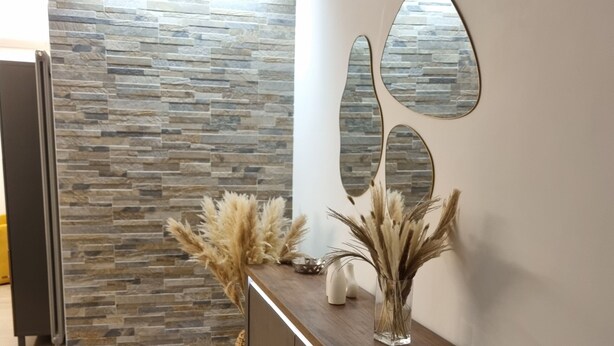 A reception area with a stone wall, a wooden reception desk, and decorative pampas grass. - Delightful apartment recently renovated, central area well connected (Roma)