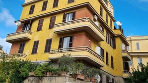A multi-story yellow building with balconies, windows, and a clear blue sky. - Delightful apartment recently renovated, central area well connected (Roma)