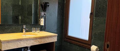 A modern bathroom with a wooden vanity, a mirror, a hairdryer, and a toilet.