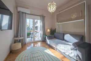Un salon moderne avec un canapé, une lampe, une petite table et une grande fenêtre avec des rideaux.