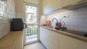 Une cuisine moderne avec des armoires blanches, un plan de travail en bois et une vue sur le balcon.