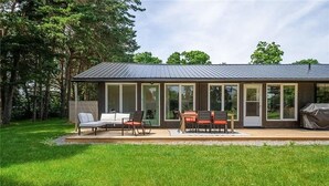Una casa moderna con terraza, mobiliario exterior y zona de barbacoa.