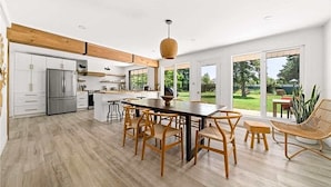 Una cocina amplia con una isla central, sillas de madera y una gran mesa de comedor.