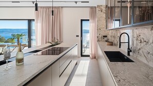 Een moderne keuken met uitzicht op zee, voorzien van een inbouwfornuis en een groot raam.