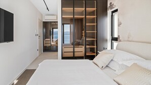 Een moderne hotelkamer met een groot bed, een inloopkast en uitzicht op zee.
