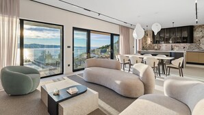 Een moderne woonkamer met een gebogen bank, een glazen salontafel en uitzicht op een meer.