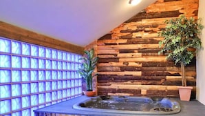 Ein Wellnessbereich mit Holzwand, Whirlpool und zwei Blumentöpfen.