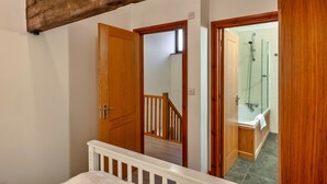 Eine Holztreppe führt zu einem Badezimmer mit Dusche und Badewanne.
