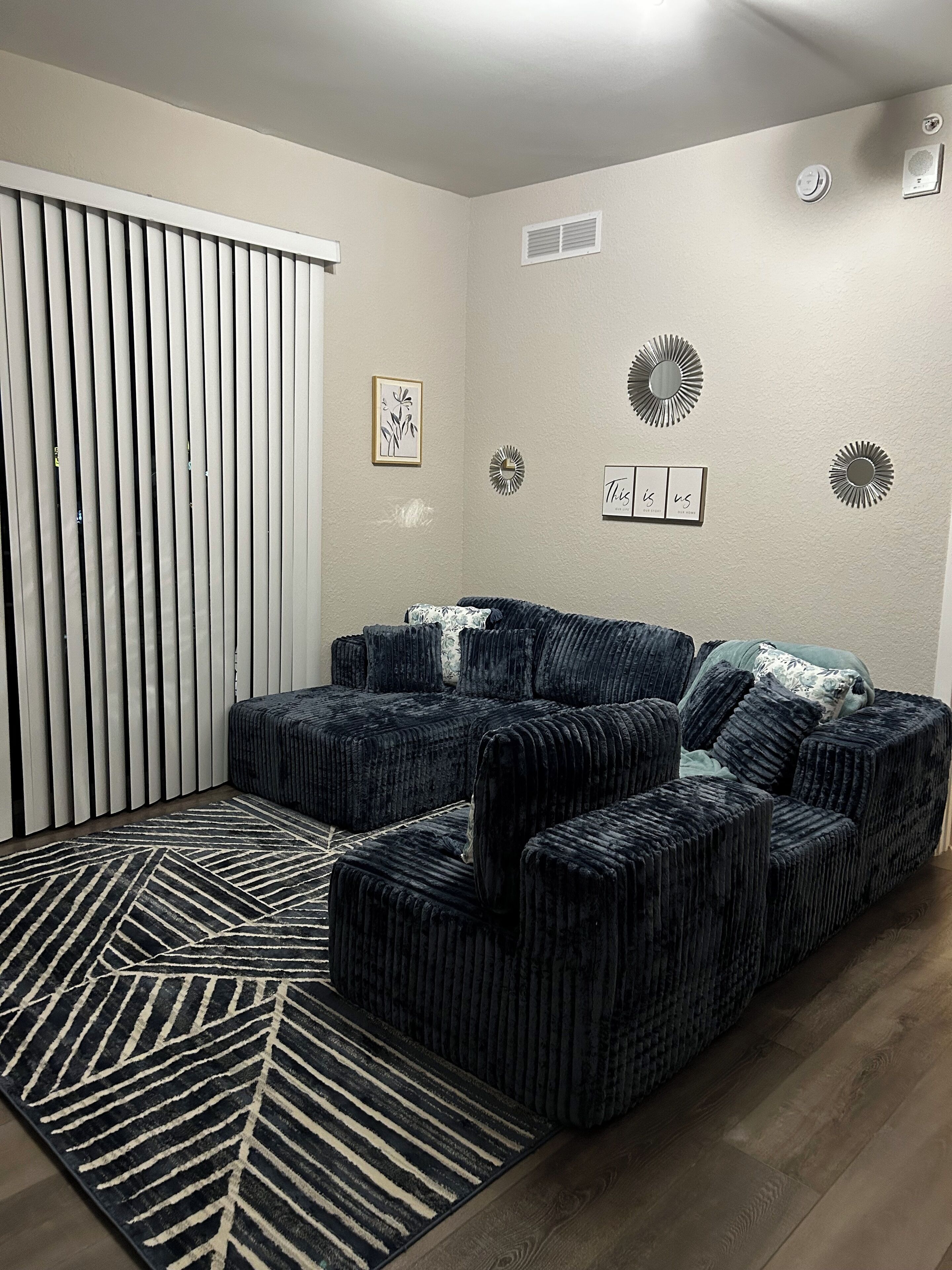 A living room with a sectional sofa, a patterned rug, and decorative wall art.