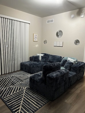 Ein Wohnzimmer mit einer Eckcouch, einem gemusterten Teppich und Wanddekoration.