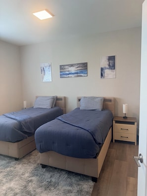 Ein Schlafzimmer mit zwei Betten, einem Nachttisch und einer Wandleuchte.