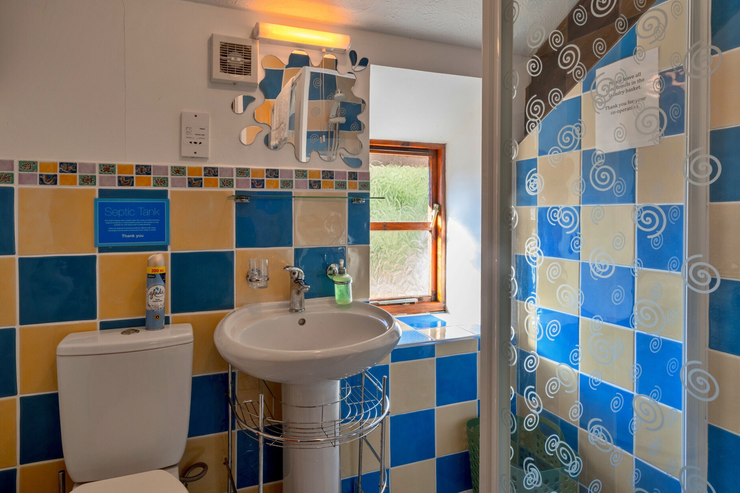A bathroom with a toilet, sink, and window.