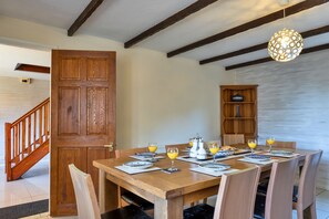 Un coin repas avec une table en bois mise pour le petit-déjeuner, comprenant des assiettes, des verres et une machine à café.