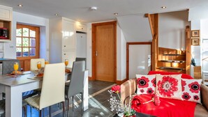 Eine moderne Küche mit Essbereich, einer Treppe und einem Wohnzimmer mit rotem Sofa und blumigen Kissen.