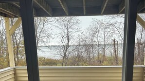 A covered outdoor area with a glass door, a round table, and two chairs. - Perfect Wells Maine getaway, Village by the Sea Condo! (Wells)