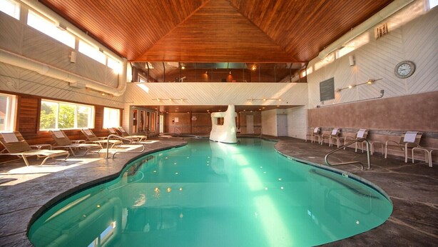 An indoor swimming pool with wooden ceiling and walls, sunlit areas, and lounge chairs. - Perfect Wells Maine getaway, Village by the Sea Condo! (Wells)