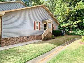 A single-story house with a front porch, a brick foundation, and a well-maintained lawn. - Modern Family Living – Near Food, I-85 & Hospital (Henderson)