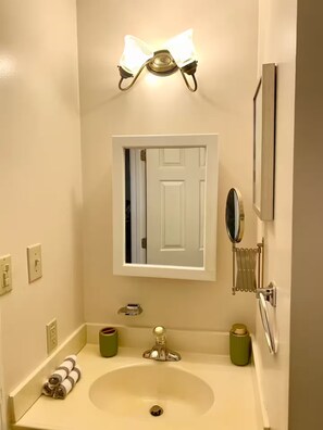 A bathroom with a sink, mirror, towel rack, and wall-mounted light fixture. - Modern Family Living – Near Food, I-85 & Hospital (Henderson)