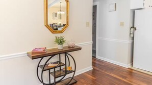 Un couloir avec une console en bois, un miroir et une plante en pot.