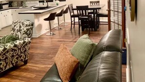 Un salon moderne avec un canapé en cuir, un fauteuil à motifs et un coin repas comprenant une table et des chaises.