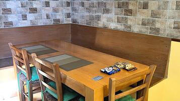 A dining area with a wooden table and chairs, a tiled backsplash, and a yellow wall.