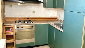 A compact kitchen with a gas stove, oven, and a sink. - All'Orologio 2 Camere Terrazza Vista (San Donato Val Di Comino)