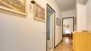 Un couloir avec une armoire en bois, une porte donnant sur une autre pièce et des œuvres d’art encadrées accrochées aux murs.