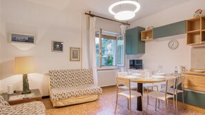 Une pièce confortable avec un canapé, une table à manger et des chaises, une lampe et une vue sur l’extérieur.