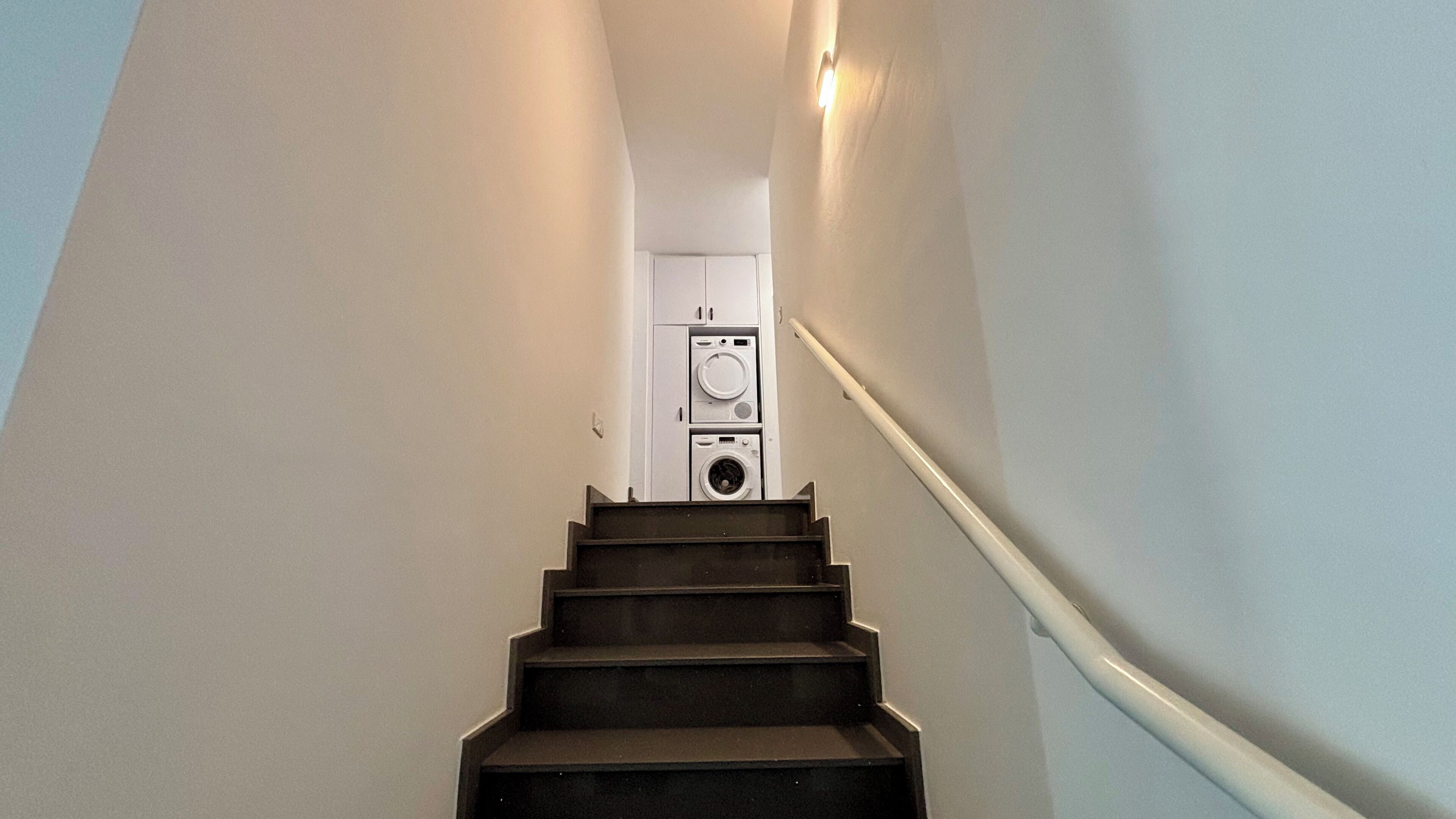 A staircase leading to a laundry room with a washing machine and dryer.
