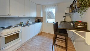 A compact kitchen with white cabinets, a stove, and a window with sheer curtains. - 2 bedroom awesome home in Sösdala (Sösdala)