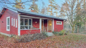 A red wooden house with a porch, surrounded by trees and fallen leaves. - 2 bedroom awesome home in Sösdala (Sösdala)