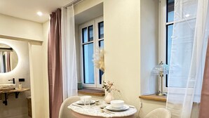 A modern dining area with a round table, two chairs, a vase with dried flowers, and a window with curtains. - Apartment 'Fewo Sand 10 - Klein' with Shared Terrace, Garden, and Wi-Fi (Bamberg)