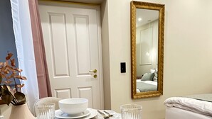 A neatly set dining table with white plates, bowls, and gold cutlery, a vase with dried flowers, and a mirror on the wall. - Apartment 'Fewo Sand 10 - Klein' with Shared Terrace, Garden, and Wi-Fi (Bamberg)