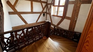 A room with exposed wooden beams, a window, and a wooden staircase. - Apartment 'Fewo Sand 10 - Klein' with Shared Terrace, Garden, and Wi-Fi (Bamberg)