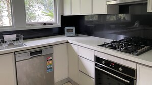 Une cuisine moderne avec des meubles blancs, un lave-vaisselle encastré, un grille-pain, une cuisinière à gaz et un four.