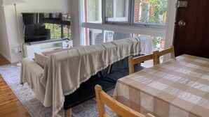 Une pièce confortable avec un lit, une table, une télévision et une fenêtre donnant sur un paysage verdoyant.