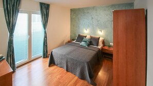 A bedroom with a bed, nightstands, a wardrobe, and a window with curtains. - Nice apartment in Stara Novalja with heated swimming pool (Stara Novalja)