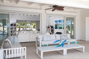 A modern living room with a white sofa set, a coffee table with decorative items, and a ceiling fan. - Encore   Tropical Gardens and Ocean Views (Saint Martin)