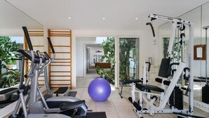 Un gimnàs a casa amb equip d'exercici, una pilota gran i un mirall.