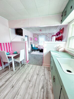 Interior - Rhinestone Cowgirl is a chic pink-inspired upper-level apartment just blocks from downtown Russell. Enjoy a cozy bedroom, living area with Smart TV, kitchenette, full bath, private balcony, and shared backyard with grill, firepit, and laundry. (Russell)