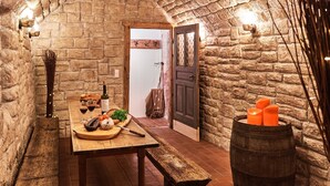 A rustic stone-walled room with a wooden table set for a meal, a bench, and a barrel with candles. - Holiday Home Lilace with Hot Tub, Fireplace, 4 Bedrooms, Max. 8 Guests (Böttingen)