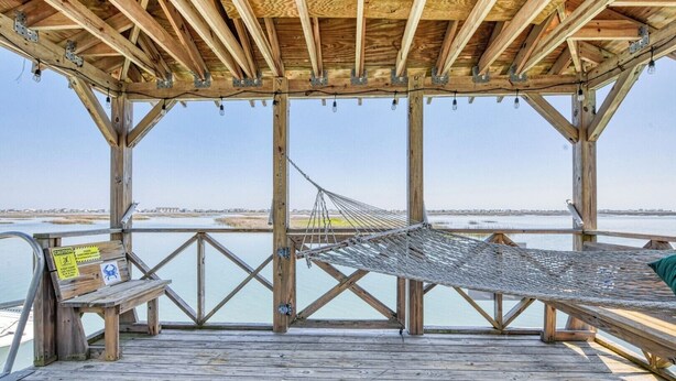 A wooden deck with a hammock, a bench, and a caution sign. - 4 Bedroom 2 Bath Inlet Front Home with Deep Water Access (Murrells Inlet)
