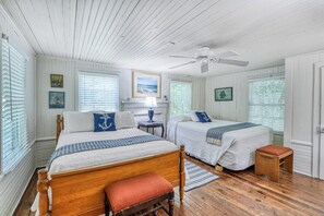 A room with two beds, a ceiling fan, wooden flooring, and a view of the outdoors through the windows. - 4 Bedroom 2 Bath Inlet Front Home with Deep Water Access (Murrells Inlet)