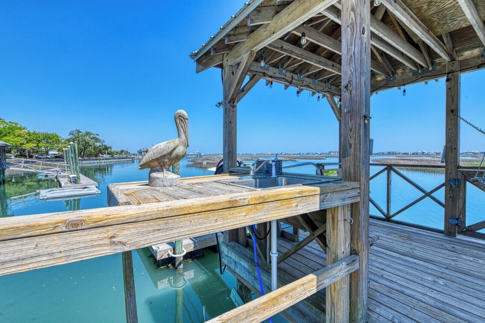 A wooden pier with a sink and a pelican sculpture.