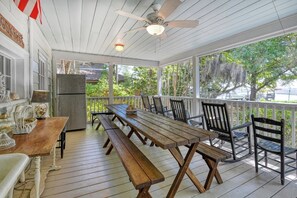 A covered porch with a wooden table and chairs, a ceiling fan, and a view of trees and a river. - 4 Bedroom 2 Bath Inlet Front Home with Deep Water Access (Murrells Inlet)