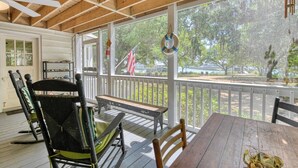 A covered porch with a table and chairs, a ceiling fan, and a view of a wooded area. - 4 Bedroom 2 Bath Inlet Front Home with Deep Water Access (Murrells Inlet)