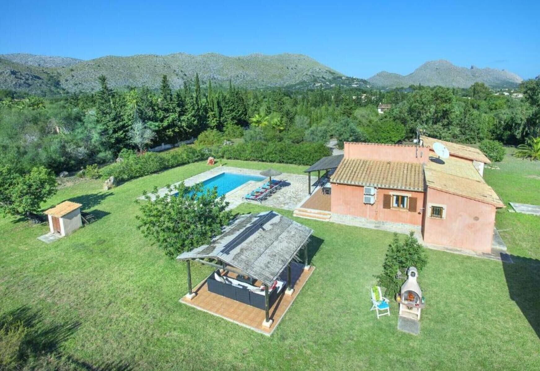 Finca mallorquina con piscina privada, amplio jardín y vistas a la sierra en un entorno natural.