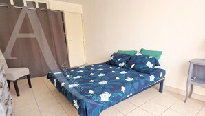A bedroom with a bed, a chair, and a small table. - GRAND T2 AVEC TERRASSE, GARAGE ET PISCINE (Sète)