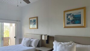 A hotel room with two beds, a ceiling fan, and two framed paintings on the walls. - Queen Deluxe Double at Boundless Bliss Hotel (Southside)