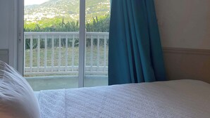 Et hotelværelse med en seng, udsigt til en balkon og et gardin.